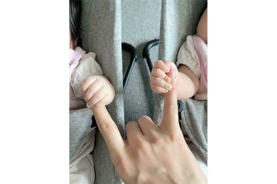 双子に指を握られる大山加奈さん、2人の子供の成長を日々感じている【写真：本人提供】