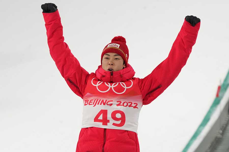 銀メダルを獲得し、表彰台で両手を挙げて喜ぶ小林陵侑【写真：AP】