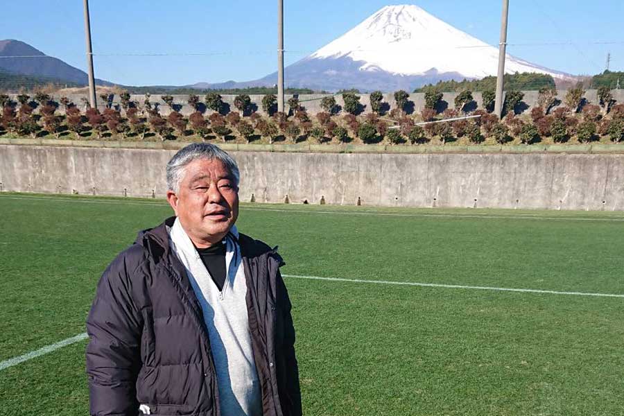 富士山を背にして、時之栖スポーツセンターの天然芝グラウンドに立る上間政彦氏