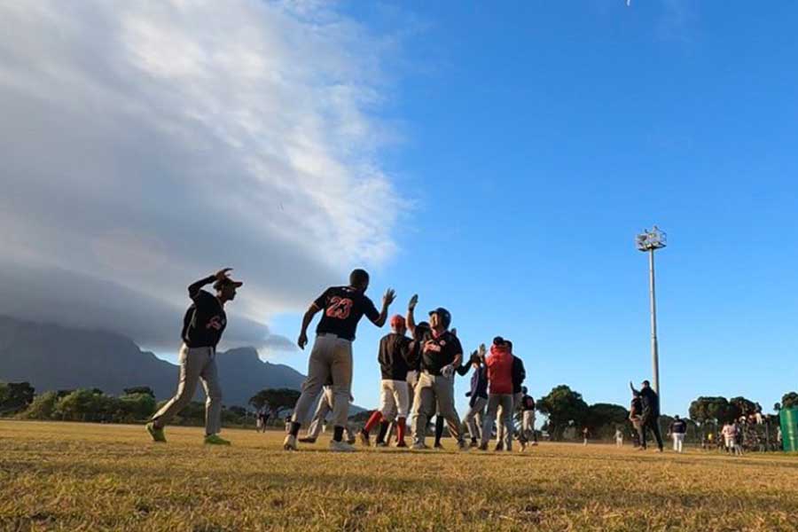 南アフリカのリーグでチームメートとハイタッチする返田岳（中央）。背景にはケープタウンの象徴であるテーブルマウンテンに雲がかかっている【写真：本人提供】