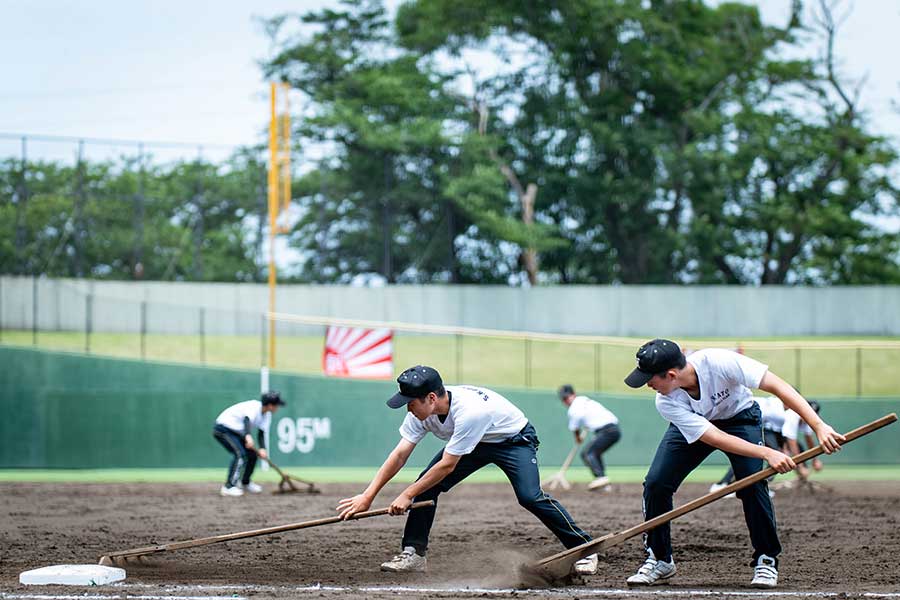 大会初日、保土ヶ谷球場でトンボ掛けをする横浜隼人の補助員たち、スタンドからは拍手が送られた【写真：中戸川知世】