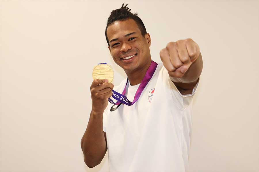 10月のアジア大会で獲得した金メダルを手にポーズを取る岡澤【写真：浜田洋平】