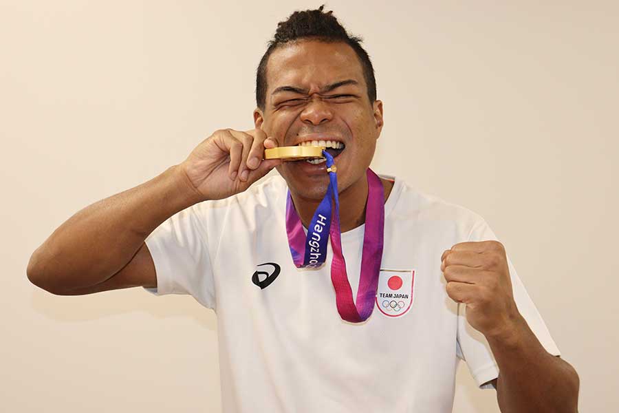 10月のアジア大会で獲得した金メダルを自ら噛んでみせた岡澤、明るいキャラで仲間に愛されている【写真：浜田洋平】