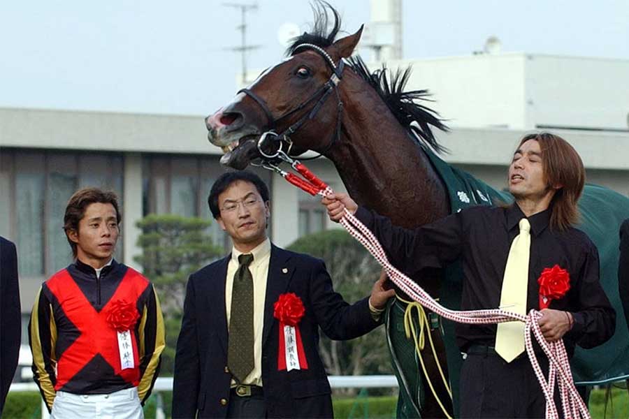 2004年の菊花賞を勝利したデルタブルースと岩田康誠騎手（左）、角居勝彦調教師（左から2人目）【写真：産経新聞社】