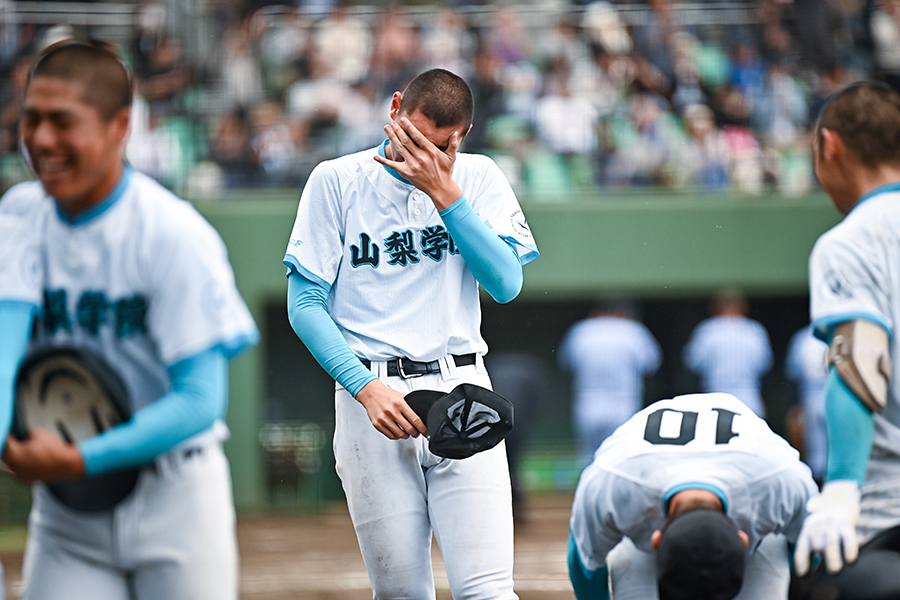 試合終了の整列後、ベンチへ戻りながら左手で顔を覆い、涙を拭う山梨学院の菰田陽生【写真：中戸川知世】