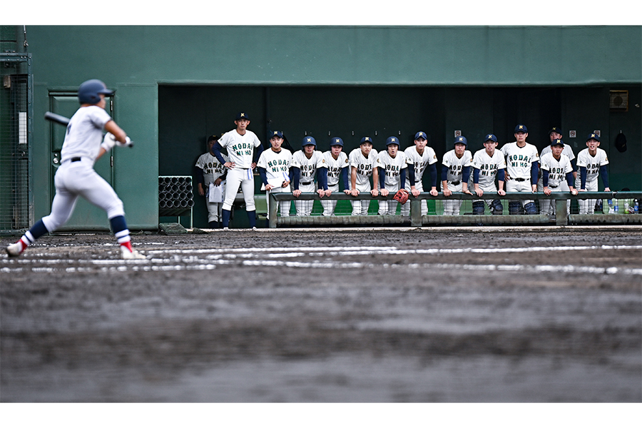 ベンチの左側に身を寄せ合い、一球に集中しながら試合を見る東農大二ナイン【写真：中戸川知世】