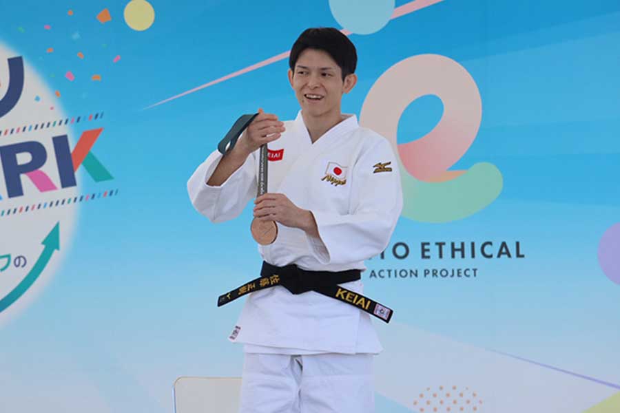 登壇しメダルを掲げた佐藤正樹【写真:横田美咲】
