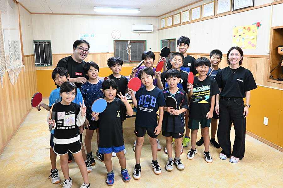 ハッピー学童クラブの與那覇雅之代表（左奥）、娘の美優さん（右端）と笑顔の子どもたち【写真：長嶺真輝】