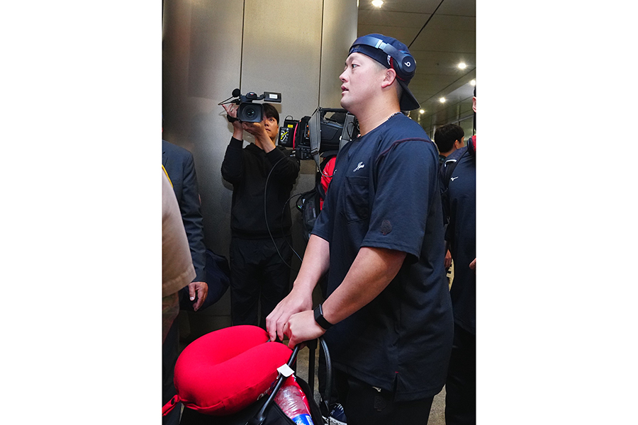 ヘッドホンを頭につけてマイアミ空港に到着した侍ジャパンの牧秀悟【写真：荒川祐史】