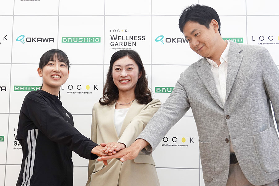 岡田氏(中央)と手を合わせる梅野倖子(左)、石井大裕GM【写真:編集部】