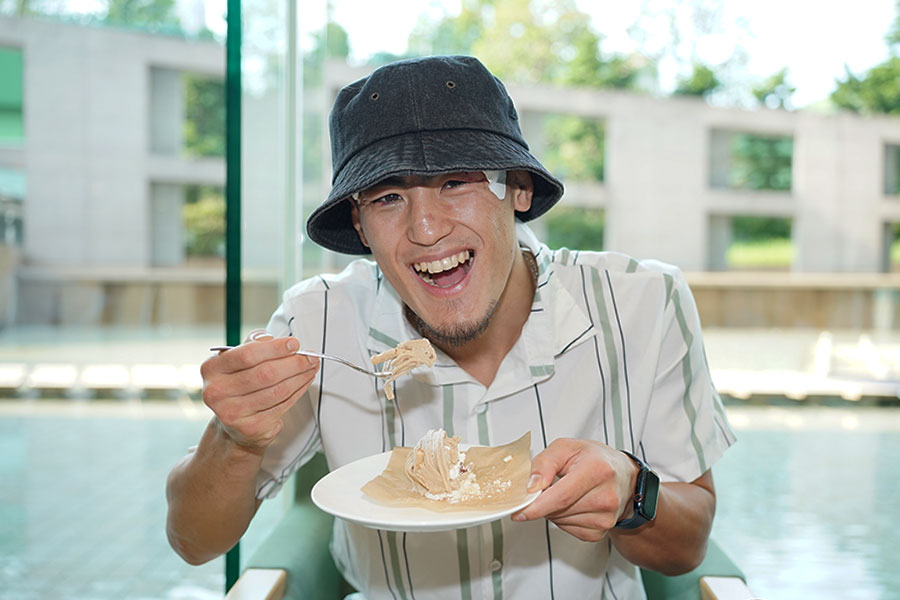 一夜明けで取材に応じ、モンブランをほおばる秋次克真【写真:澤田直人】