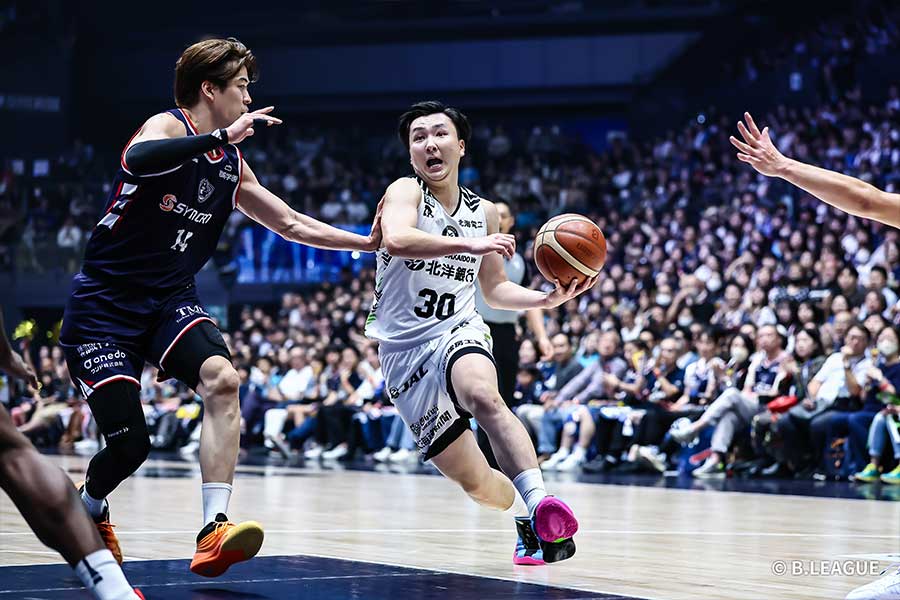 佐藤卓磨（左）にマークされながらもゴールを狙う富永啓生【写真提供：Bリーグ】